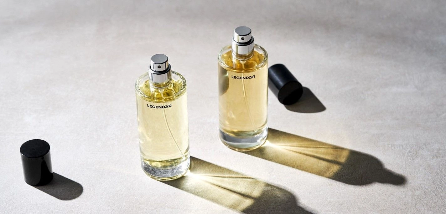 Zwei geöffnete Eau de Parfum Flakons von Legendär mit Licht- und Schattenspiel auf hellem Untergrund