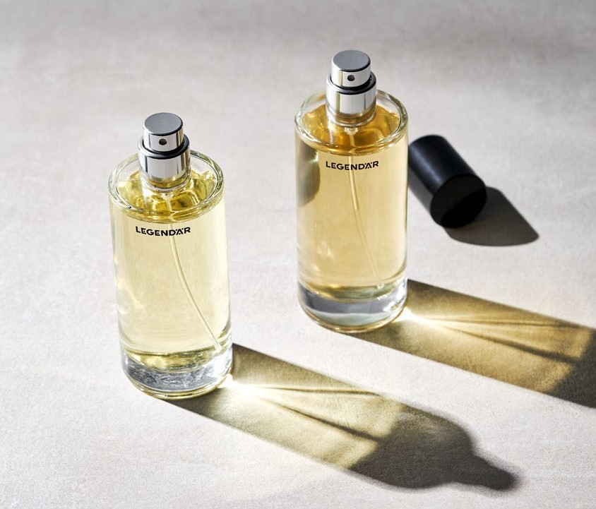 Zwei geöffnete Legendär Eau de Parfum Flakons mit Lichtreflexionen auf hellem Untergrund in Betonoptik